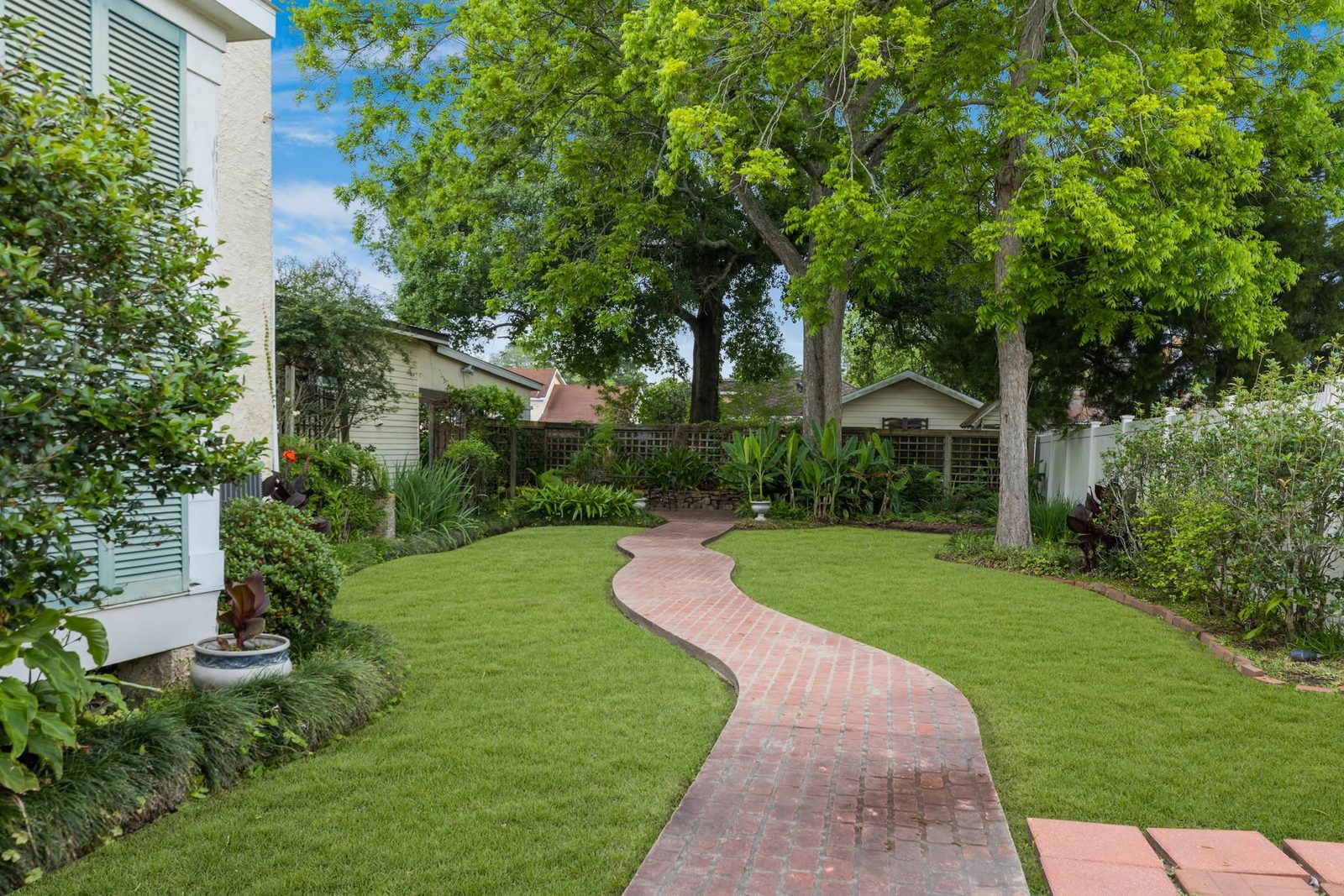 The East Garden at The Caldwell House — brick path and lawn beneath the oaks